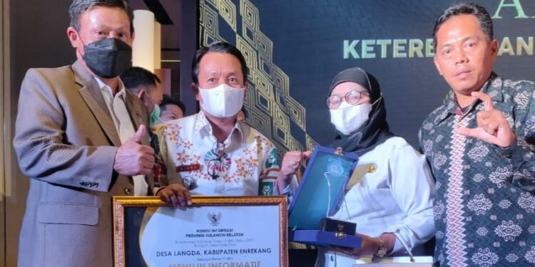 Kades Langda, Risal didampingi Kadis DPMD Enrekang dan Kadis Diskominfo Enrekang tampak memegang penghargaan yang diberikan oleh Sekda Provinsi Sulsel Abdul Hayat Gani didampingi Komisioner Komisi Informasi, Pahit Halim. --ist--