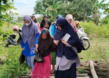 Kadis Sosial Sidrap Wahida Alwi (Kanan) Membantu Idempo (Tengah) Melewati Jembatan, Jumat (7/02/2025). Foto--Tohir/PIJARNEWS)