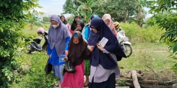 Kadis Sosial Sidrap Wahida Alwi (Kanan) Membantu Idempo (Tengah) Melewati Jembatan, Jumat (7/02/2025). Foto--Tohir/PIJARNEWS)