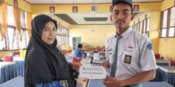 KETGAM: Guru SMKN 5 Jeneponto, Satrina, S.Pd, mendampingi Alamsyah Ramadhan menerima bantuan tunai dari pemprov Sulsel, Senin, 18 Mei 2026.